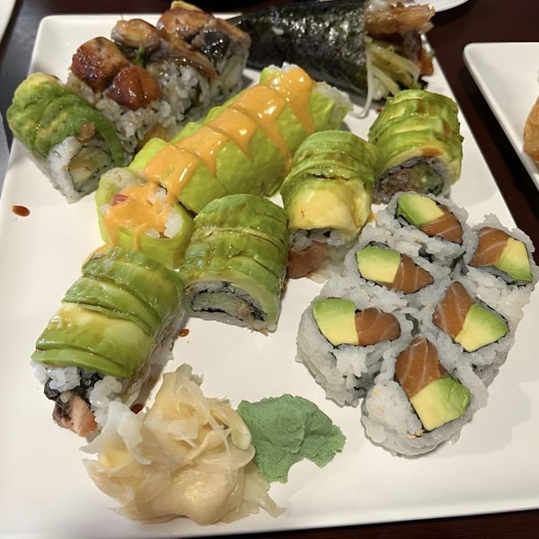 A white plate filled with various Sushi Palace sushi rolls, including avocado, salmon, and eel.