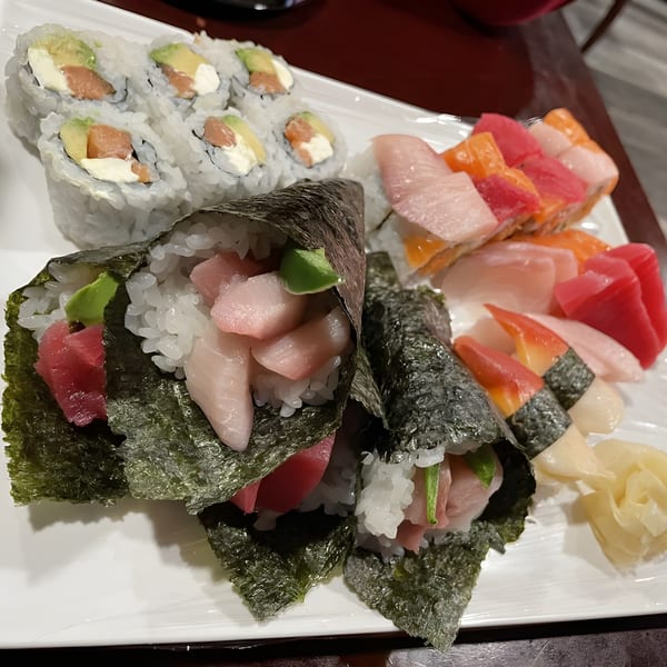 A white platter of Sushi Palace's sushi rolls, hand rolls, nigiri, and sashimi.