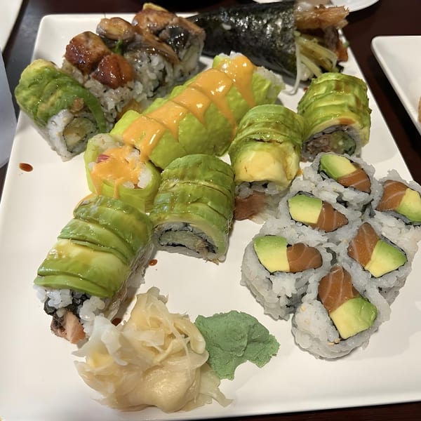 A white plate filled with various Sushi Palace sushi rolls, including avocado, salmon, and eel.