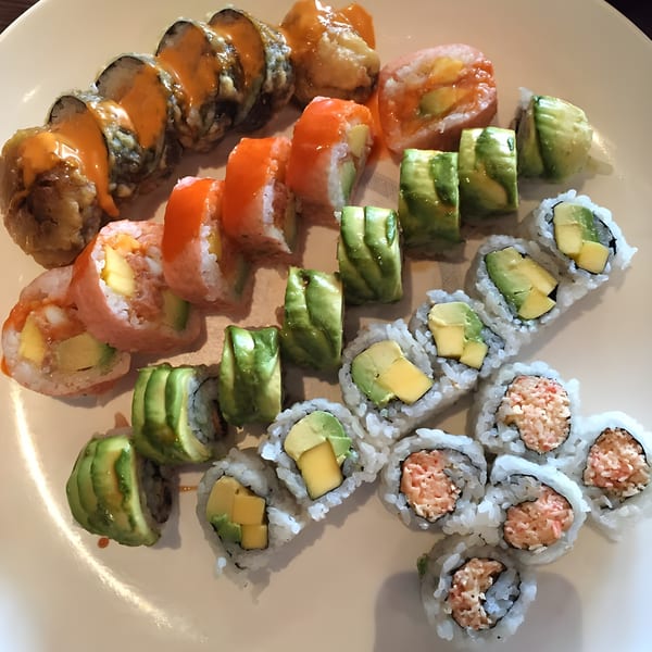 A white plate filled with various Sushi Palace sushi rolls, including avocado, mango, and spicy tuna.