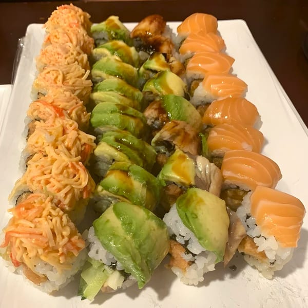A platter of Sushi Palace sushi rolls, including salmon, avocado, and crab-topped varieties.