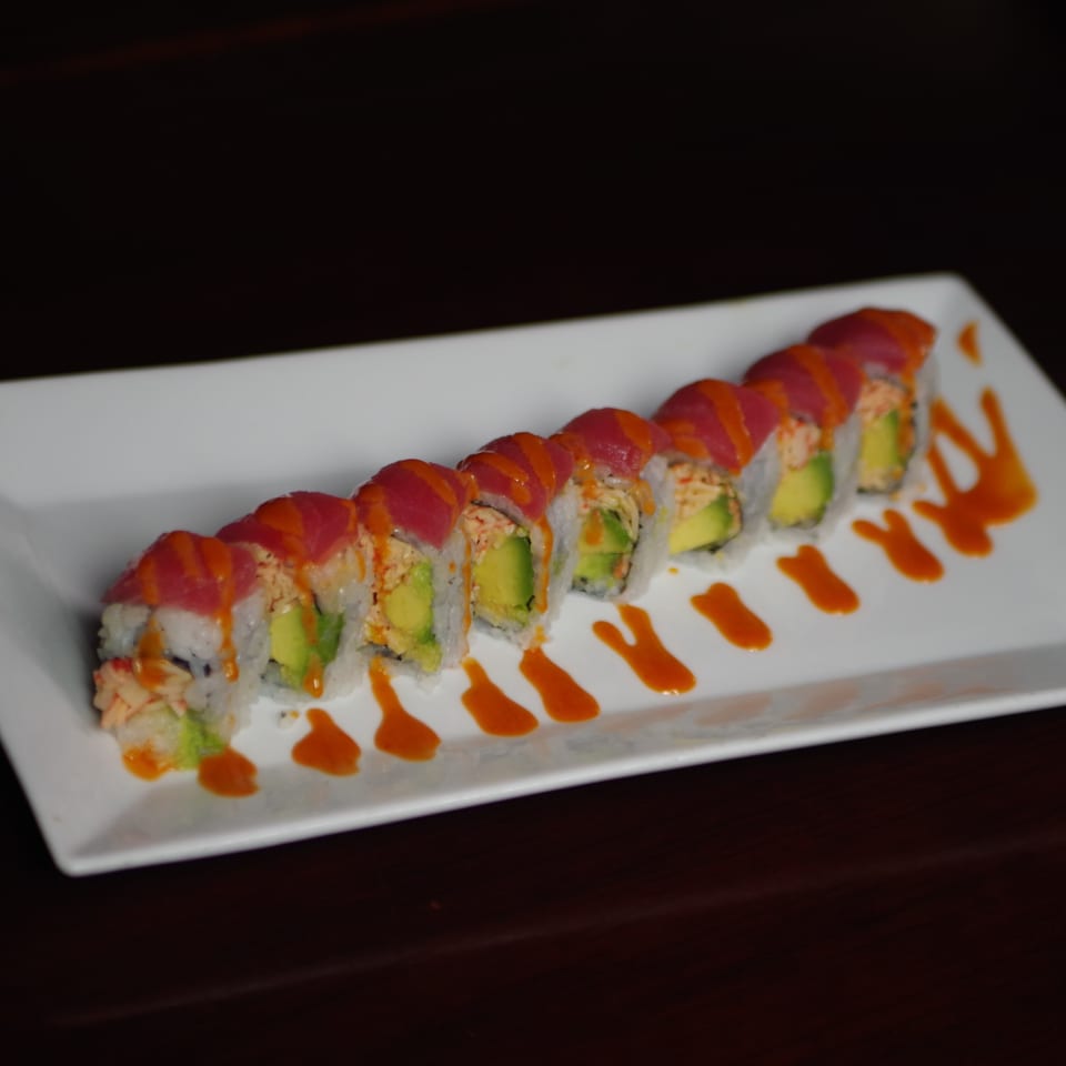 Sushi Palace's vibrant sushi roll with tuna, avocado, and crab, drizzled with orange sauce.