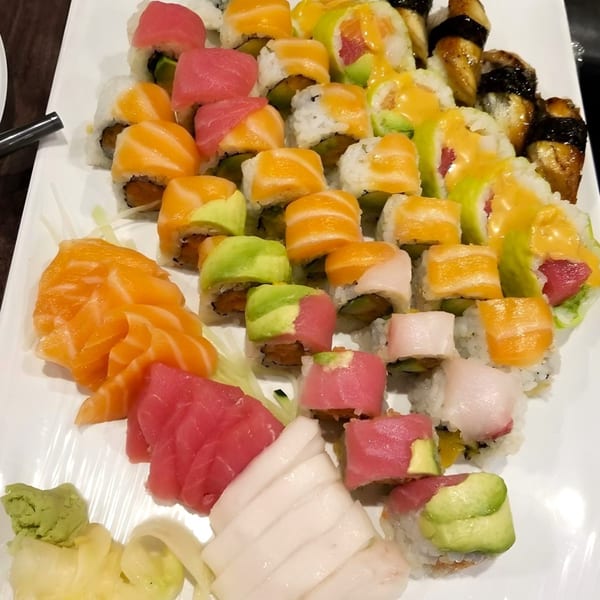 A large white platter filled with various colorful sushi rolls, sashimi, wasabi, and ginger.